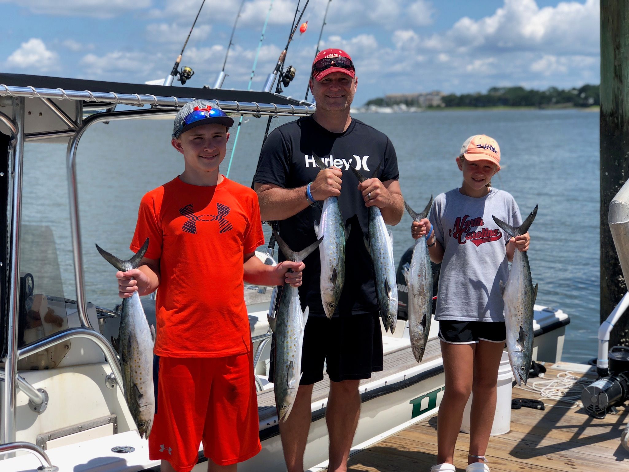 Three anglers holding Spanish mackerel at the dock